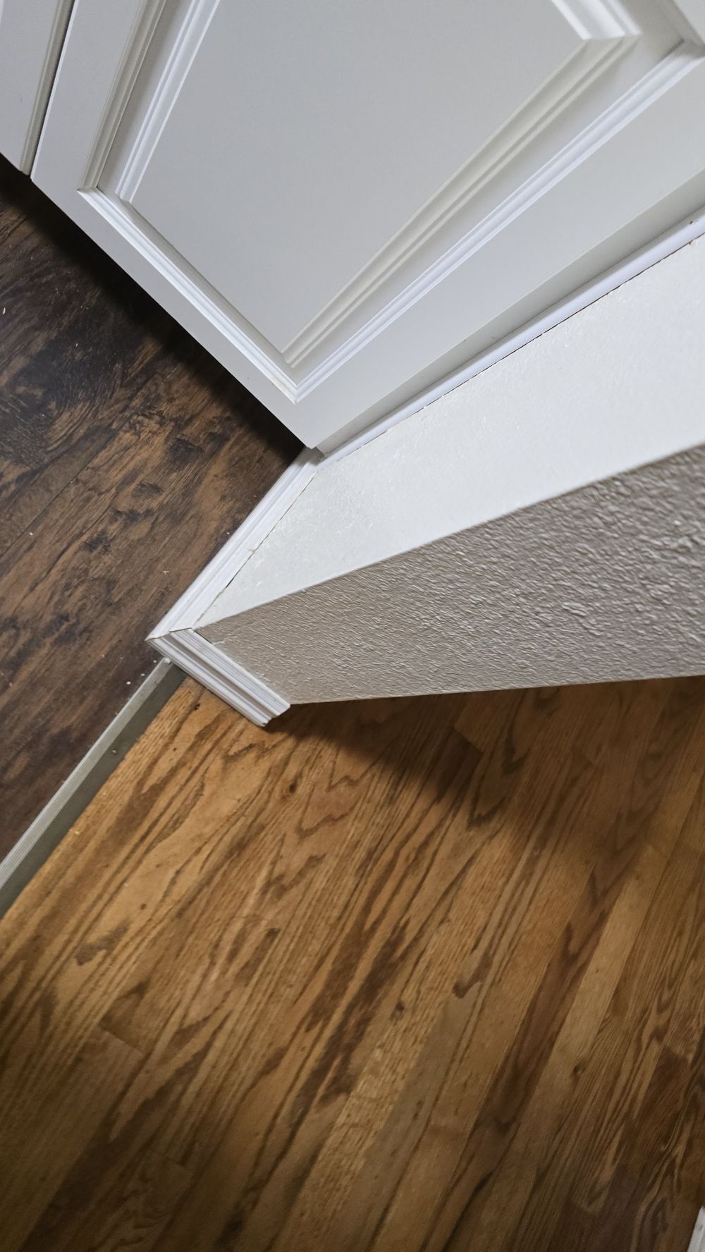 White baseboard and door casing finished against a hardwood floor