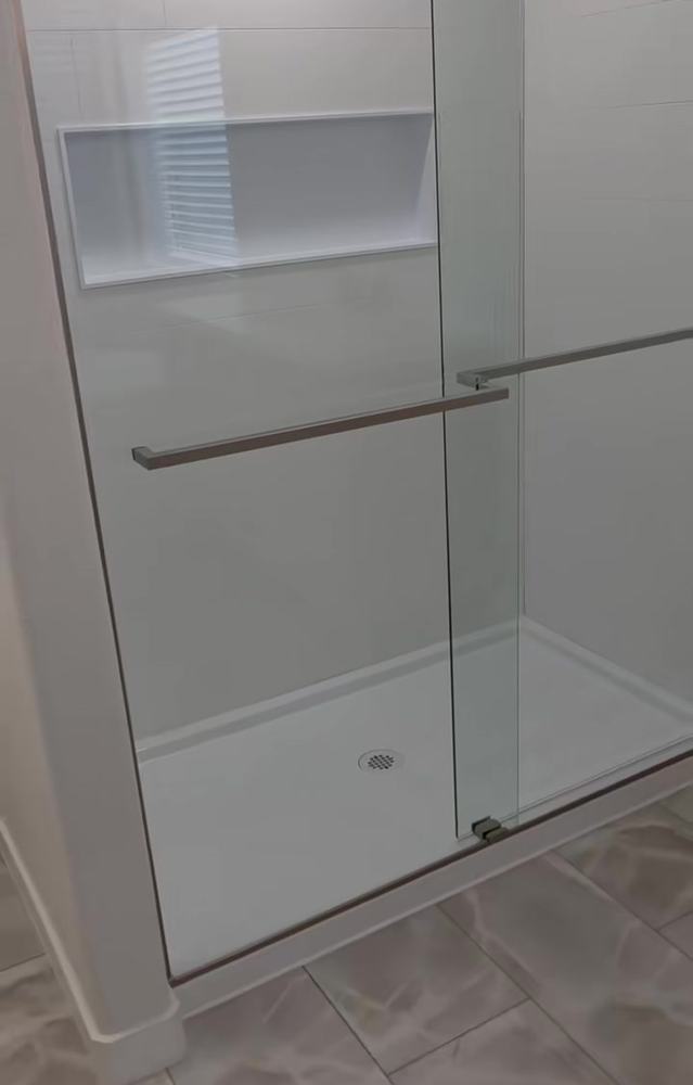 Walk-in shower with sliding glass doors and a recessed niche