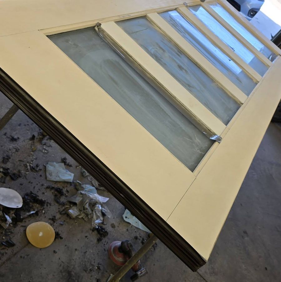 Entry door with glass lites stripped and sanded back to bare wood on a shop bench