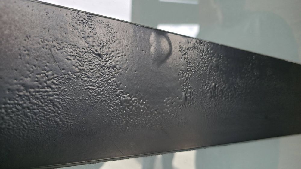 Close-up of the entry door's old dark finish, bubbled and failing