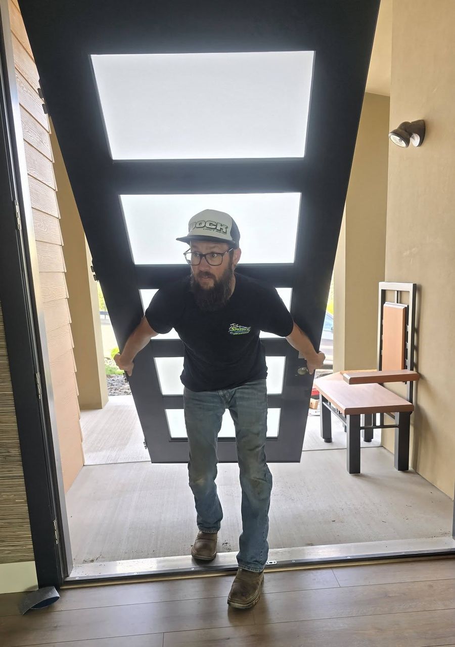 Carrying the refinished entry door slab back in through the front doorway