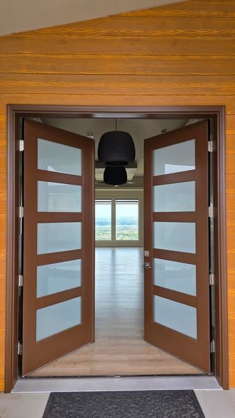 Refinished brown double entry doors standing open, with frosted glass lites