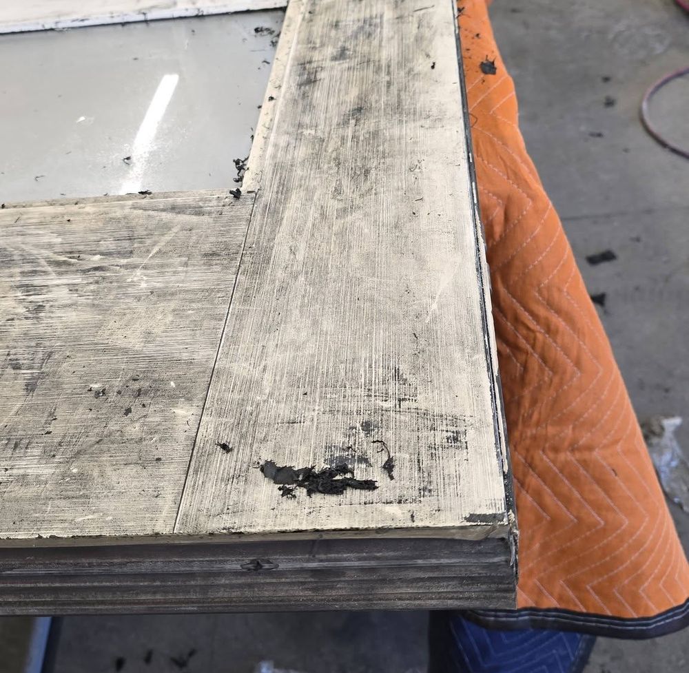 Entry door rail stripped of its old finish on a padded shop bench