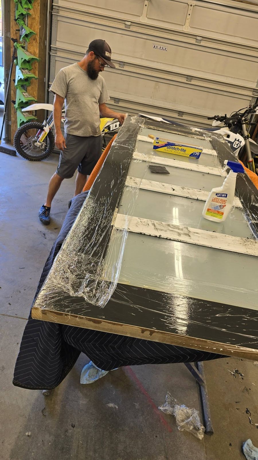 Stripping the old finish off an entry door at a padded bench in the shop