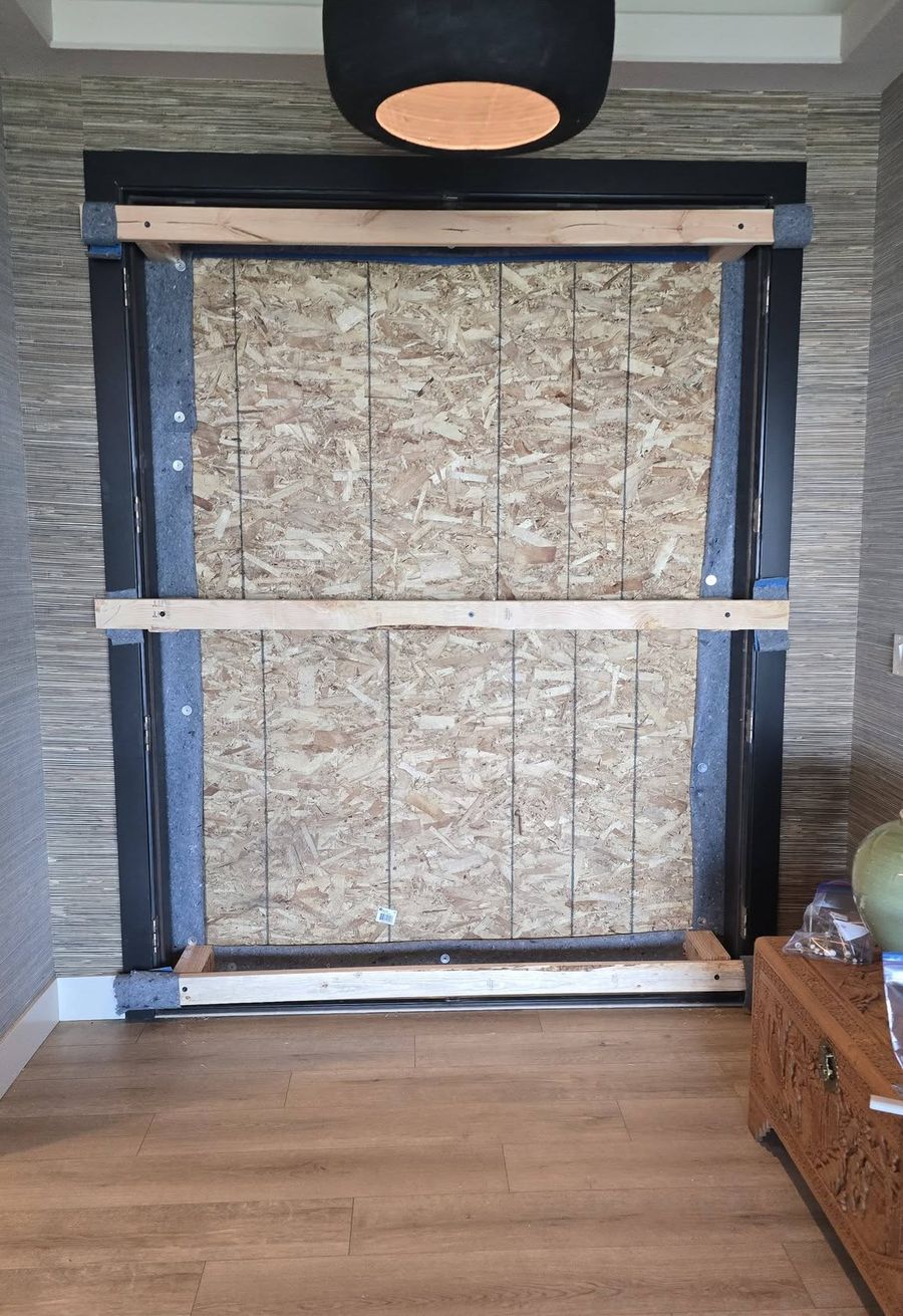 Entry door opening boarded up with OSB and lumber braces while the door was in the shop