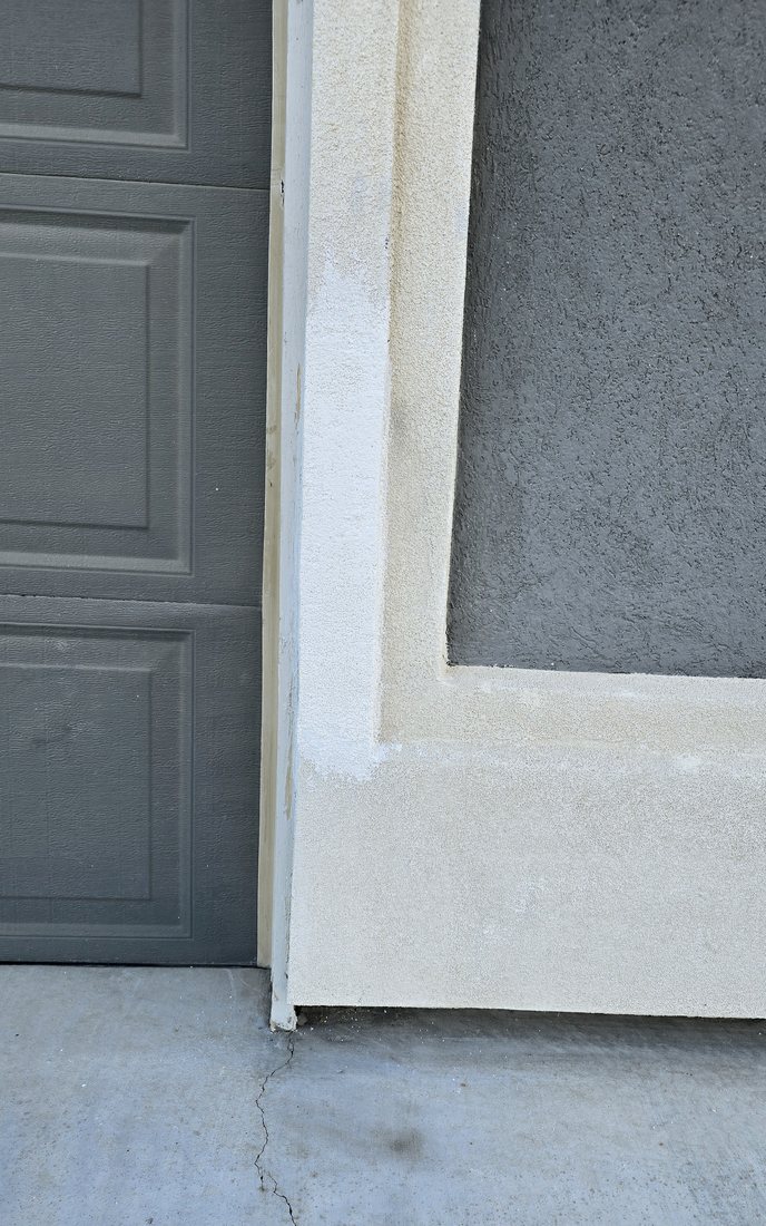 Garage door frame trim and stucco repaired and painted to match the house