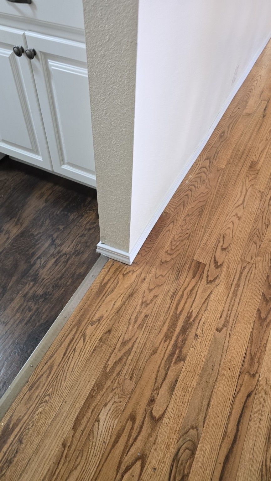 Wood-look floor running cleanly from the kitchen into the hall