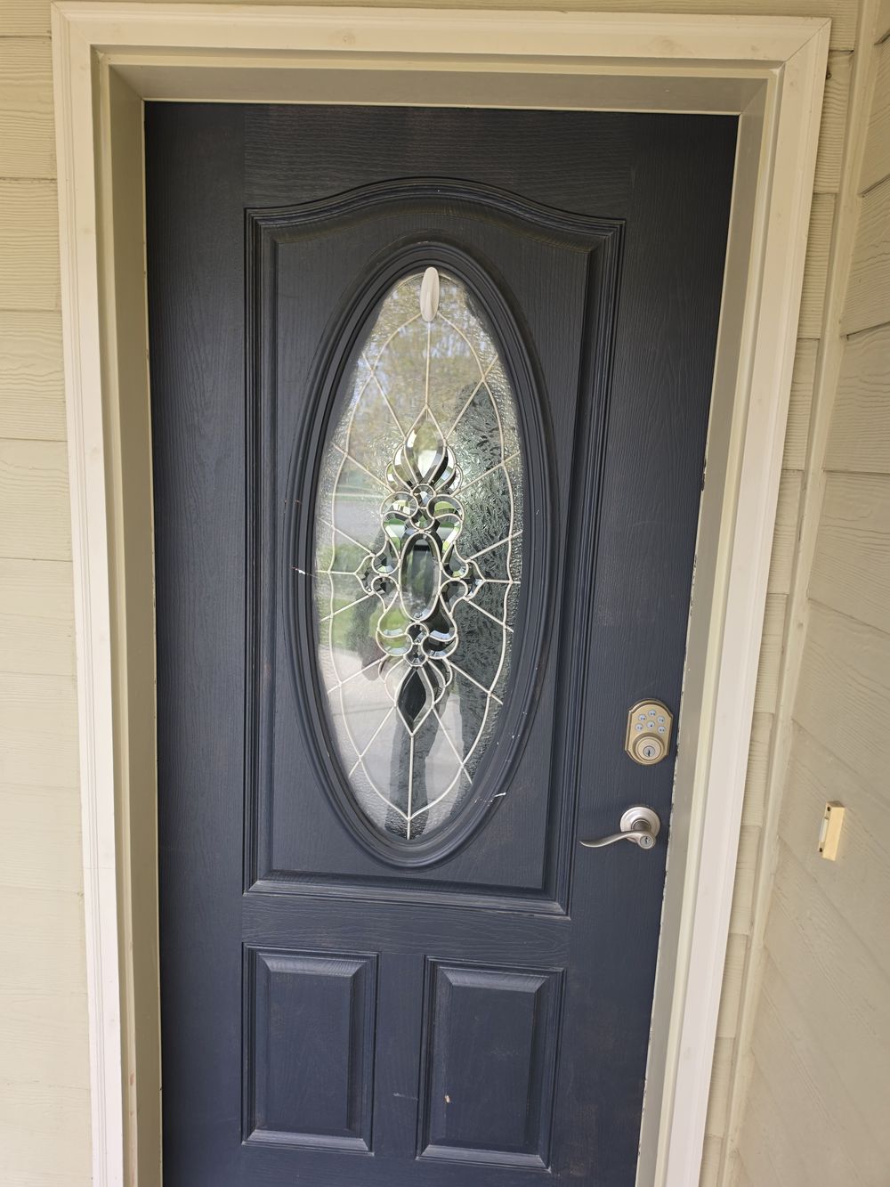 Front entry door with oval glass after Speedy's re-caulked the casing with color-matched caulk