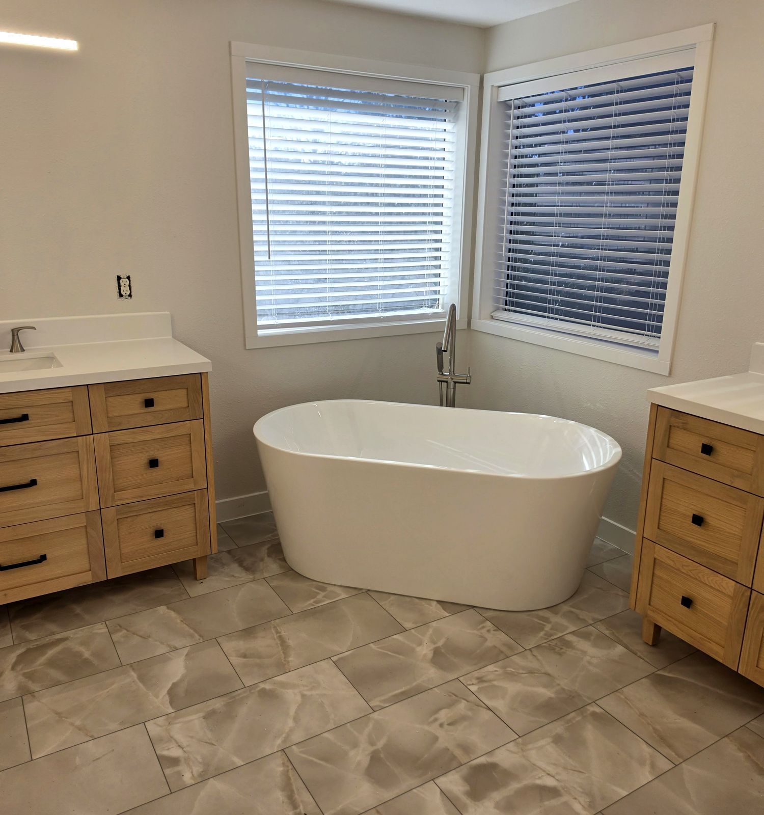 Finished bathroom remodel by Speedy's Handyman in Kennewick: freestanding tub, two wood vanities with quartz tops and new tile floor
