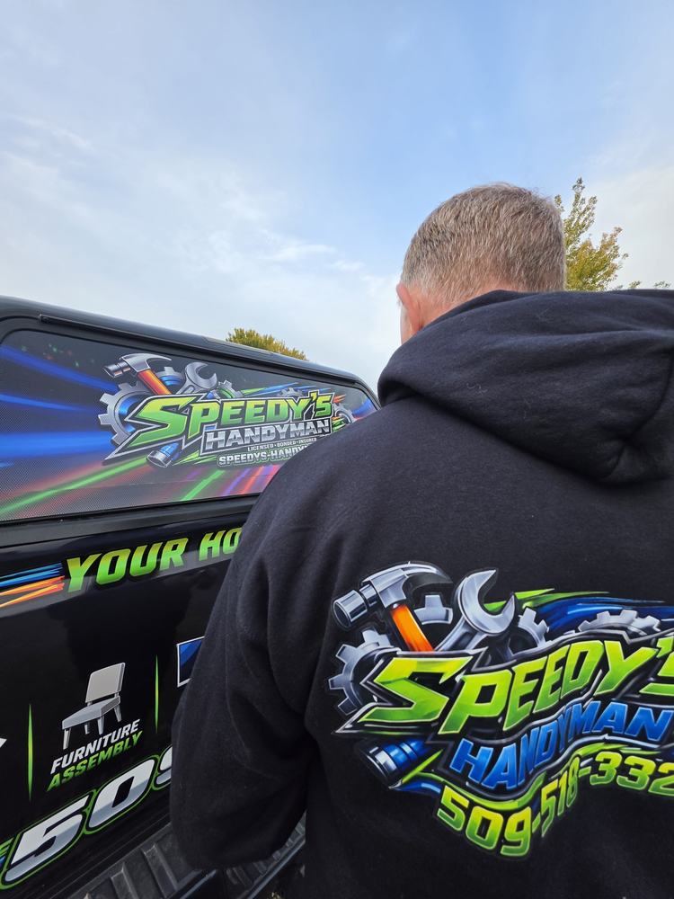 James Hoidal, owner of Speedy's Handyman, in a Speedy's hoodie beside the wrapped work truck