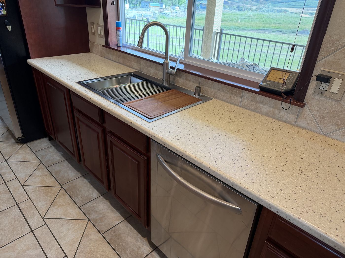 Workstation sink and faucet in place under a kitchen window after a sink replacement