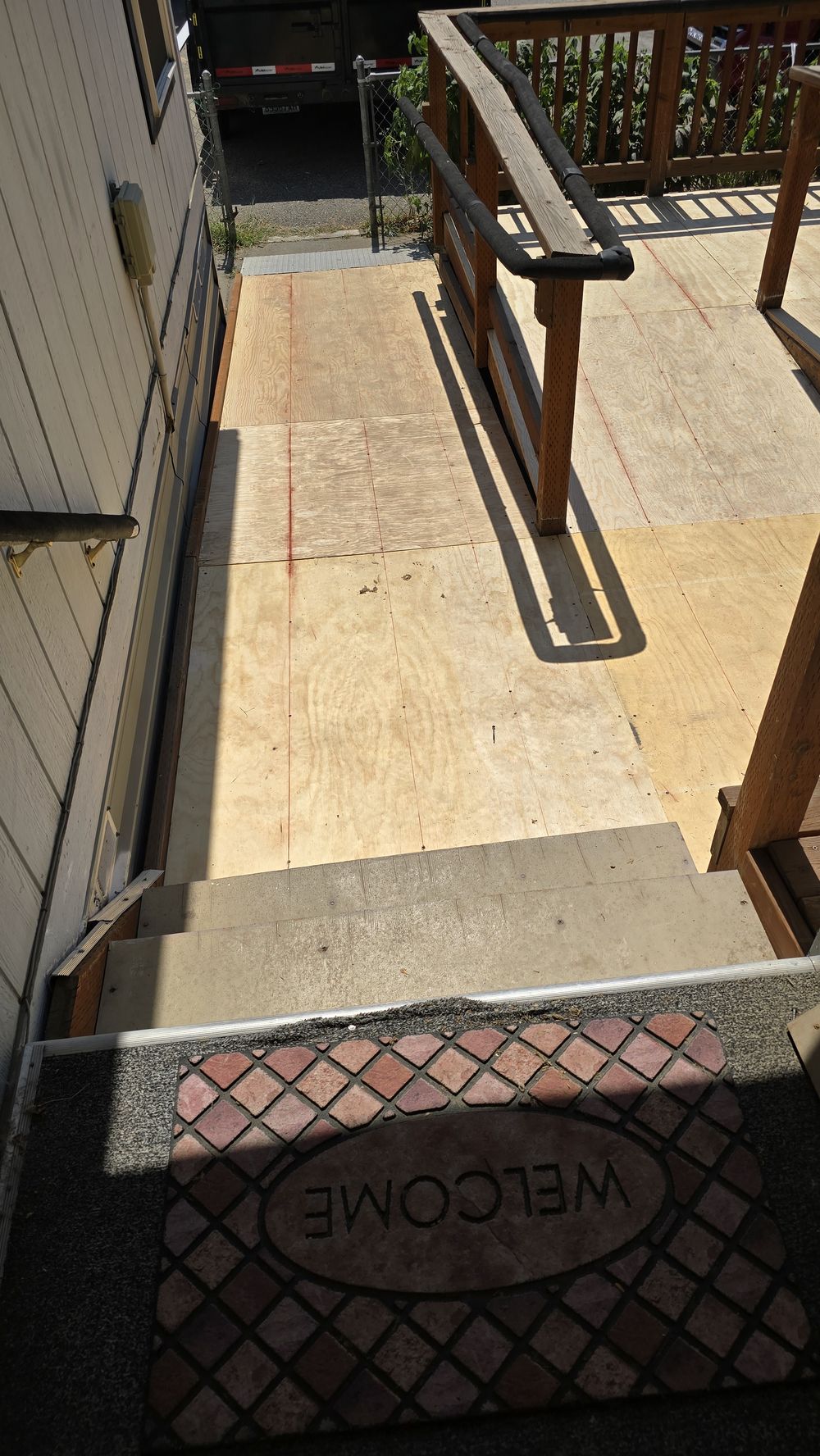 Finished wood entry ramp with a handrail running down to the walkway